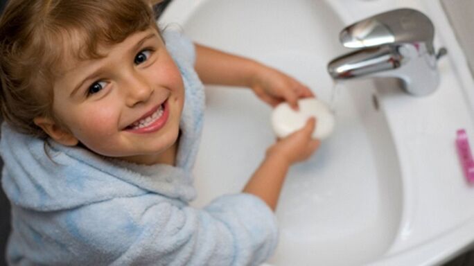L'enfant se lave les mains avec du savon pour éviter les vers.